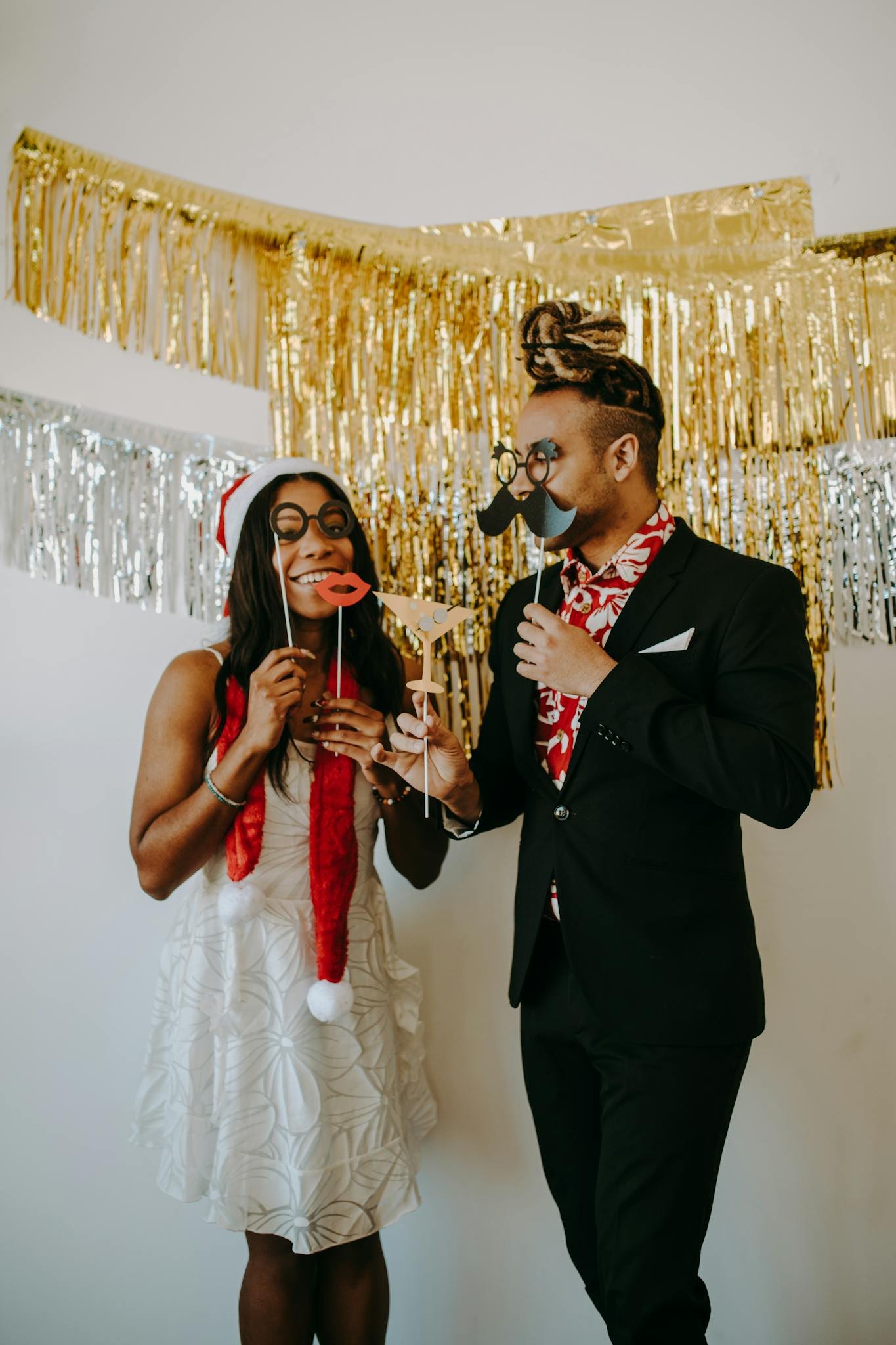 Smiling adults in festive attire posing with props during a holiday party.